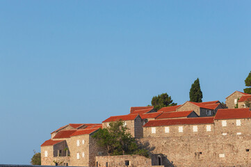 Sveti Stefan Island Hotel, stone houses of a medieval fortress village with tiled roofs on the Adriatic coast of Montenegro