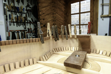 Close-up of kerfing and linings held by clothespins inside handmade flamenco guitar
