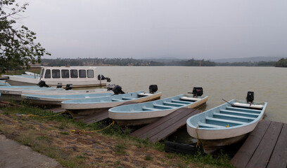 Conjunto de lanchas aparcadas en muelle con laguna al fondo y cielo nublado