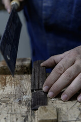 Close-up of luthier cutting wooden guitar bridge piece