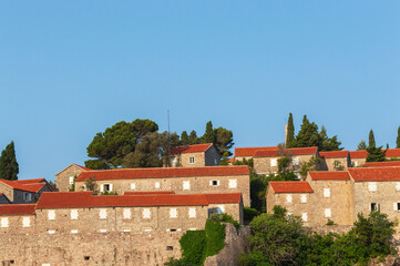 Sveti Stefan Island Hotel, stone houses of a medieval fortress village with tiled roofs on the Adriatic coast of Montenegro