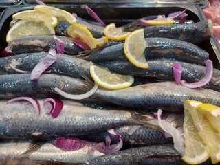 Herring with red onion rings and lemon. 