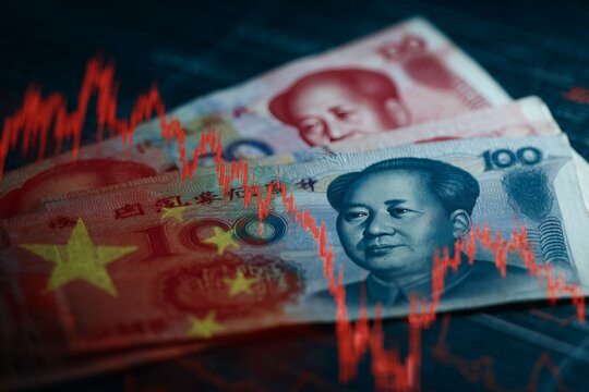Chinese yuan currency notes against stock market graph with bearish trend