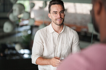 Confident Young Male Professional In Glasses And White Button-Down Shirt Having Business Discussion In Modern Office
