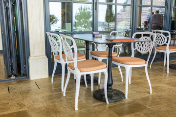 Modern restaurant terrace with set tables and chairs. Casual dining, cozy atmosphere, and summer hospitality experience.