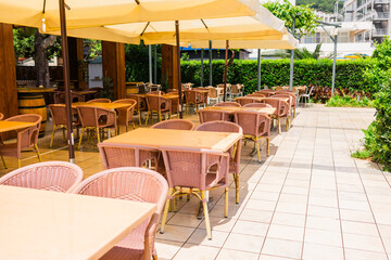 Modern restaurant terrace with set tables and chairs. Casual dining, cozy atmosphere, and summer hospitality experience.