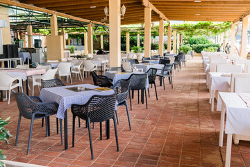 Modern restaurant terrace with set tables and chairs. Casual dining, cozy atmosphere, and summer hospitality experience.