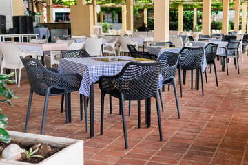 Modern restaurant terrace with set tables and chairs. Casual dining, cozy atmosphere, and summer hospitality experience.
