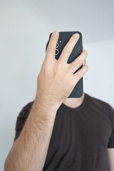 Close-up of the phone instead of the man's face on the light gray background. Mobile and social media in everyday life.
