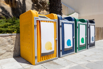 Colorful recycling bins and labeled trash containers placed on the beach. Waste separation bins...