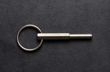 Small hexagonal metal keyring tool isolated on dark background