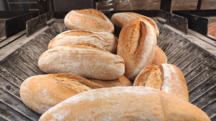 Freshly baked artisanal bread loaves arranged in a rustic wooden tray with flour dusting