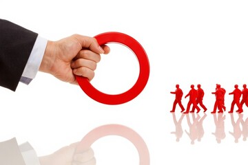 Businessman's hand using magnet to attract red team of miniature figures on white background