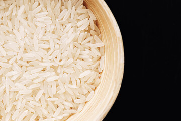 White basmati rice in wooden bowl. Raw grains arranged in dish. Organic plant-based food. Simple...