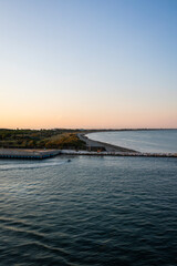 A breathtaking sunset over the Venetian waters, highlighting a lighthouse and the silhouette of the coastline. The golden hues reflect beautifully on the rippling waves