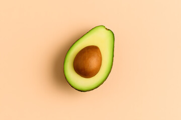 Top view of a sliced ripe avocado showing the seed, placed on a soft peach-colored background..