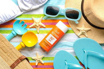 Top view of bottle of sunscreen with 50+ written on it,sunglasses and beach items. Concept of sun protection