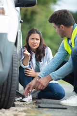 woman changes damaged wheel with help