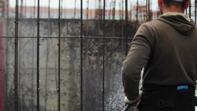 Construction worker watering concrete foundation for curing