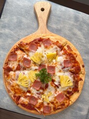 Hawaiian Pizza with Pineapple and Ham on a Wooden Plate