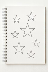 Sketch of stars drawn in black on blank notebook page  