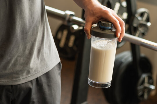 Close up of man hand with protein shaker at gym. Fitness healthy lifestyle concept. Supplement product, creatine, glutamine for workout.