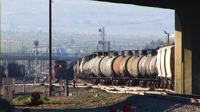 A long train of oil tanker cars and hoppers threads its way through the gritty railyard in Mojave, California.