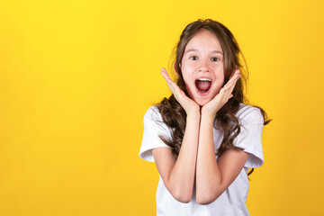Excited screaming surprised young caucasian blonde girl against yellow background