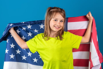 Portrait of young cheerful caucasian girl with American USA flag on blue background. Independence day 4th July concept