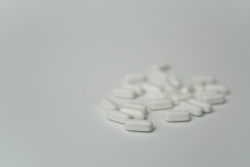 Group of white pills tablets on a light grey background 