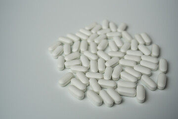 Group of white pills tablets on a light grey background top view