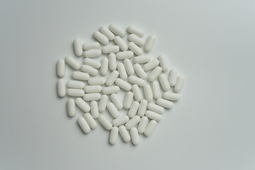 Group of white pills tablets on a light grey background top view