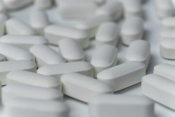 Group of white pills tablets on a light grey background close up macro