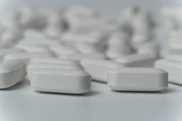 Group of white pills tablets on a light grey background close up macro