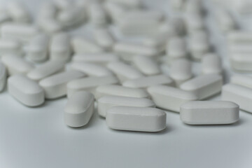 Group of white pills tablets on a light grey background close up macro