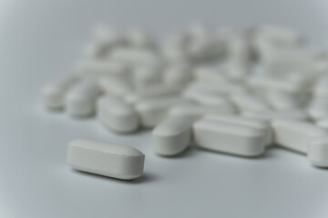 Group of white pills tablets on a light grey background close up macro