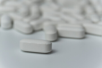 Group of white pills tablets on a light grey background close up macro