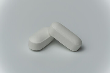 Close up macro shot of a two tablets pills on a light grey background