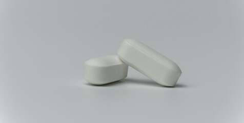 Close up macro shot of a two tablets pills on a light grey background