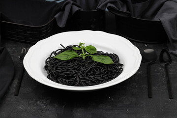 Spaghetti pasta with black ink squids on wooden background.