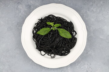 Spaghetti pasta with black ink squids on wooden background.