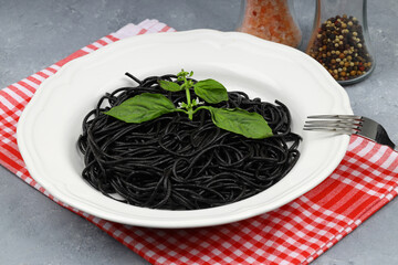 Spaghetti pasta with black ink squids on wooden background.