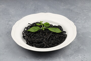 Spaghetti pasta with black ink squids on wooden background.