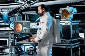 Cosmonaut in orbital station looking at monitor, preparing for mission launch to Mars. Man working...