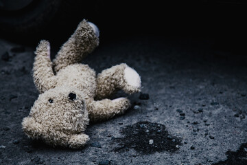 Conceptual image: lost childhood, loneliness, pain and depression. Teddy bear lying down outdoors....