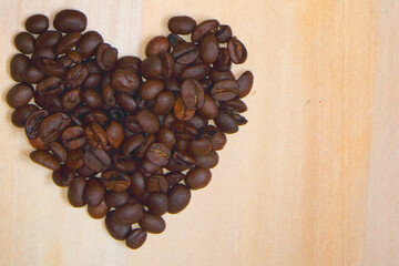 I love coffee. A heart of coffee beans against wood background. Copy space for design.