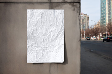 Crumpled paper sheet attached to city wall urban advert