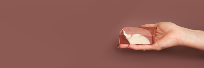  Female hand holding natural multicolored handmade solid soap on mocha mousse background. Natural...
