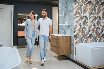 Young family couple choosing bathroom sink in bathroom fixtures store