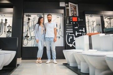 Young couple choosing lavatory pan standing together in the building shop with sanitary ceramics